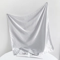 Close-up of a silver satin square scarf with a glossy finish draped over a magazine - 90*90cm / White