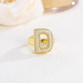Macro shot of gold-plated letter D ring set with sparkling zircon on white texture - Letter D / Gold