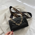 Black quilted crossbody bag with V-shaped texture and gold floral chain detail - Black