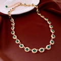 Dettaglio macro della collana vintage dorata con gemme verdi su sfondo di seta rossa - Oro-Verde
