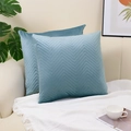 Set of two blue velvet pillow covers with quilted wave patterns on a beige sofa - Teal