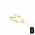 Anello aperto dorato con perle, ciondoli a cuore e zirconi su sfondo bianco puro - Stile D
