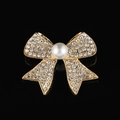 Elegante spilla a fiocco dorata con cristalli scintillanti e perla su fondo nero - Stile B213