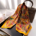 Detail of yellow paisley silk scarf elegantly draped over a leather bag and tray - Ginger Yellow