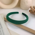 Detail of a thick green sponge headband on wood with a Hand Made woven label tag - Green