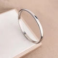 Dettaglio di un bracciale rigido minimalista in acciaio argentato con finitura lucida - Color Acciaio