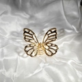Detalle de una pinza para el cabello de mariposa de metal dorado con diseño de calado - Mariposa Dorada Calada