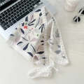 Detailed view of floral cotton triangle scarf with delicate white lace trim on a desk - Large Leaves Beige Base