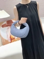 Blue hand-woven crescent handbag with knot handle detail shown by fashion model - Blue