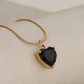Golden snake chain necklace featuring a faceted black heart pendant in a four-prong setting - Gold + Black
