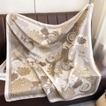 Silk-like square scarf with floral earthy print draped on a brown leather sofa - 90*90cm / Khaki