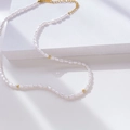 Detail of irregular baroque pearl necklace with golden beads on geometric pedestal - Rice Pearl and Gold Bead Interval