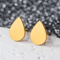 Macro shot of minimalist teardrop gold earrings on a textured white stone surface - Water Drop / Gold