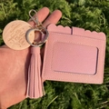 Detailed view of pink lychee leather card holder with tassel and engraved wooden charm - Pink