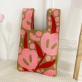 Knitted tote bag with olive green base and pink floral patterns in a cozy home setting - Pink Tulip Bag