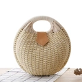 Detail of round straw handbag with circular handle and brown leather shield closure - Beige