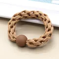 Detail eines gewebten elastischen Haargummis in Milchteebraun mit matter Kugelperle - Khaki