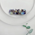 Detailed close-up of three cat-shaped acetate hair clips with marble texture on ceramic plate - Dark Blue
