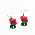 Cute green Christmas bell earrings with red bow detail on a clean textured background - Christmas Bell