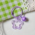 Purple acrylic star keychain with a matching bell and ring on a checkered backdrop - Transparent Purple