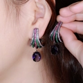 Macro shot of fan-shaped drop earrings with purple oval stones and colorful cubic zirconia - Black Gold Multi-color