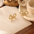 Detailed shot of gold-plated titanium steel bow earrings on a beige fabric display pad - Bowknot Beaded Earrings (ZHE490金)