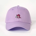 Close-up of small red dinosaur embroidery holding a coffee cup on lilac baseball cap - Light Purple