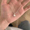Collana con pendente a stella d'argento e catena sottile tenuta in mano per dettagli - Stile Dolce Piccola Stella / Argento