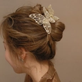 Elegant gold butterfly hair claw clip with pearls shown on a bun hairstyle for women - Pearl Style
