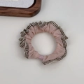Close-up of a pink fabric scrunchie featuring brown and white plaid ruffled lace edges - Pink with Coffee Plaid