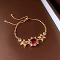 Detail of gold plated bracelet featuring a red oval gemstone and floral side accents - 22# Gold Red Gemstone Bracelet