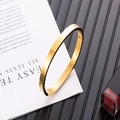 Close-up of a minimalist gold oval stainless steel bangle with side hinge closure - 6mm / Gold