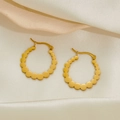 Golden titanium steel hoop earrings with scalloped edges on luxury satin background - Connected Circular Earrings