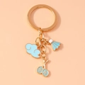 Détail du porte-clés doré avec pendentifs raquette de badminton et nuage en émail bleu - Bleu