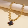 Dettaglio della collana maglione con perline dorate e ciondolo quadrifoglio vintage su stand - Forma di Quadrifoglio (Motivo Tartarugato)