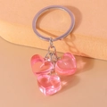 Close-up of translucent pink heart charms on a silver metal keychain accessory - Pink