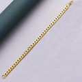 Dettaglio di un bracciale a maglia cubana dorata su sfondo bicolore curato - Oro