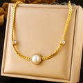 Collier chaîne plate dorée avec perle centrale et halo de cristaux sur un présentoir - N2907