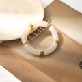 Detail of cream acrylic tube bracelet with gold metal spacers on fashion magazine - Platinum