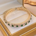 Detailed close-up of gold-plated open bangle featuring emerald green and white zircons - Bangle - Green Zircon - Square