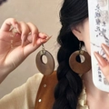 Close-up of vintage resin hoop earring with dark wood texture and copper wire detail - Coffee Round Wooden (8# Ear Hook)