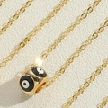 Makroaufnahme der goldenen Evil Eye Halskette mit schwarz-weißem Emaille-Anhänger - Schwarz