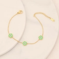 Detail of gold flower bracelet with green petals and evil eye charms on ceramic plate - Light Green
