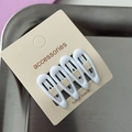 Detail view of four white star-shaped hair clips on a handmade accessories display card - White