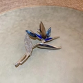 Detail der silbernen Paradiesvogel-Brosche mit blauen und grauen Kristallen auf einem Teller - Magnolie (1678)