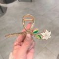 Close-up of floral hair claw clip with white enamel flower and gold alloy design - K56 Lily With Green Leaf