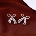 Macro view of silver bow-shaped stud earrings with zircon inlay on red silk background - Silver Earring Post Style / Silver