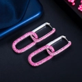 Macro detail of geometric buckle earrings with vibrant rose red pavé zircon stones - White Gold Red Zirconia