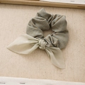 Blue and yellow plaid fabric scrunchie with light green bow on beige linen background - Green
