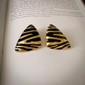 Detailed view of vintage triangle earrings with black enamel tiger stripes on an open book - 38# Antique Gold Black Irregular Triangle (Silver Earring Post)